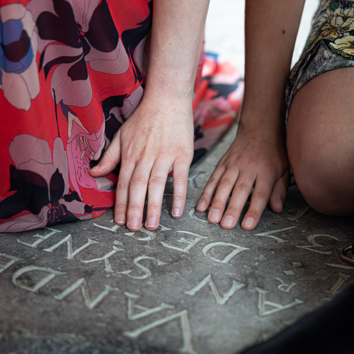 Op deze foto zijn handen van dichtbij te zien. De handen voelen aan een inscriptie op een van de grafstenen die verwerkt zijn in de vloer van de Grote Kerk Breda.